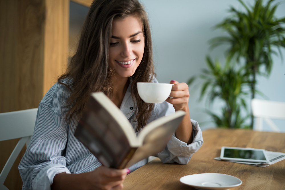 A woman reading a book and drinking coffee while taking a social media break