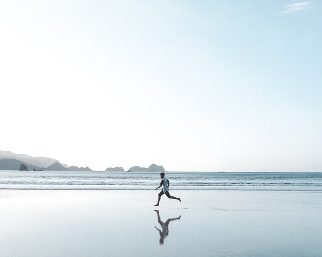 Types of Exercise: A person jogging on the beach 