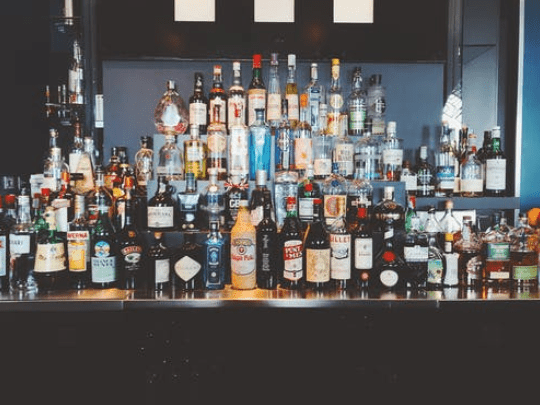 A bar top and shelves covered in various bottles of alcohol